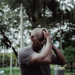 Senior man wiping sweat off his brow after working out on a hot day.