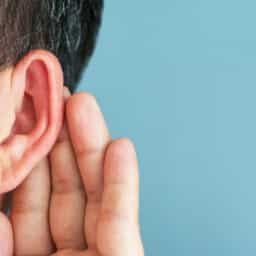 Man holds hand behind ear