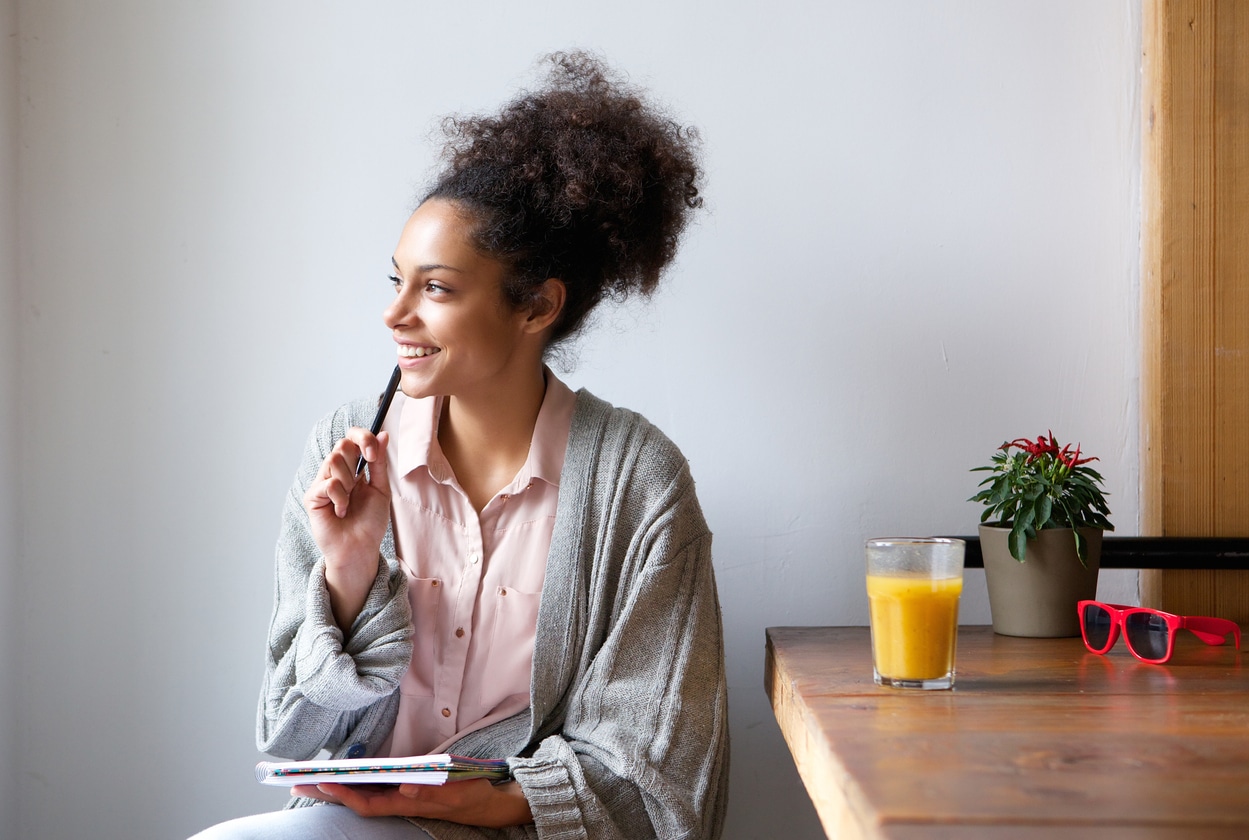 Woman with a pen and paper thinking happy thoughts.